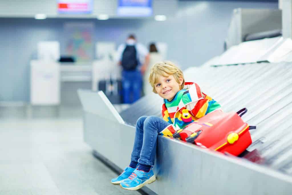 Kind op bagageband van een vliegveld