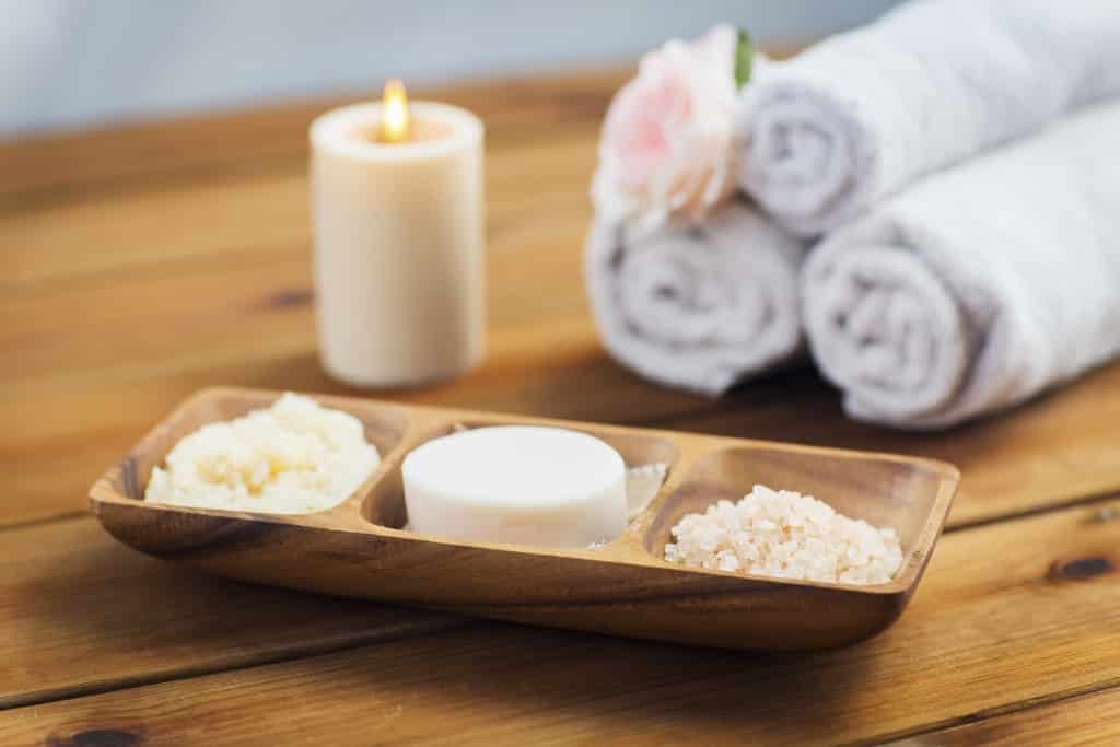 Close-up van zeep, zout en scrub bij een kaars en handdoeken