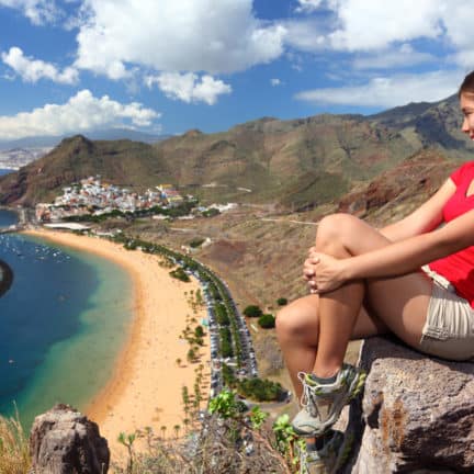 Vrouw kijkt op een rots uit over Playa De Las Teresitas op Tenerife