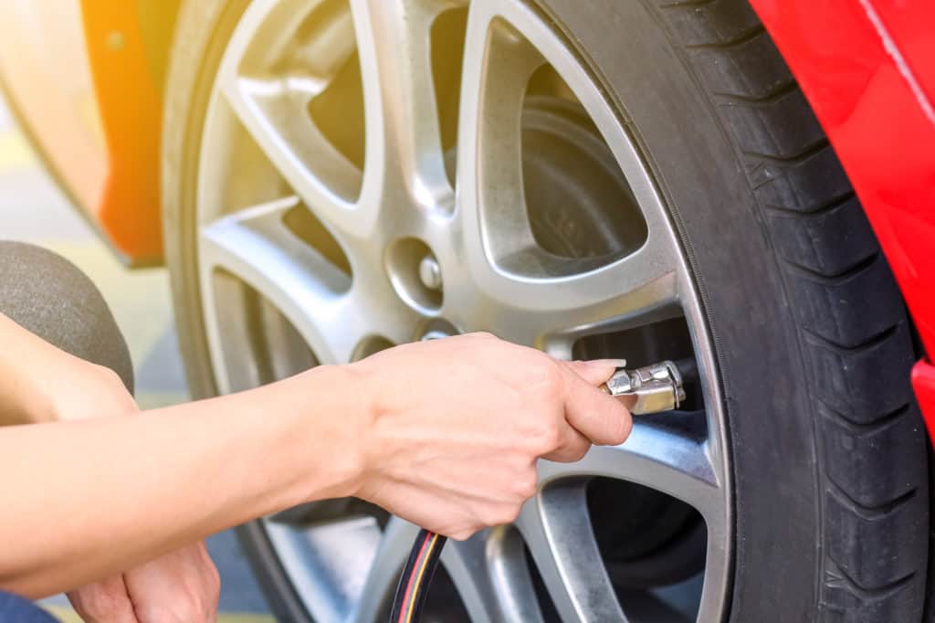 vrouw vult autoband met lucht Vrouw vult een autoband met lucht