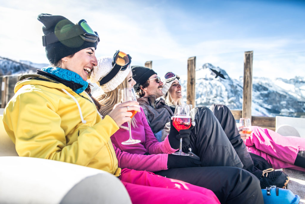 Groep vrienden in skikleding drinken wijn op een terras in de bergen