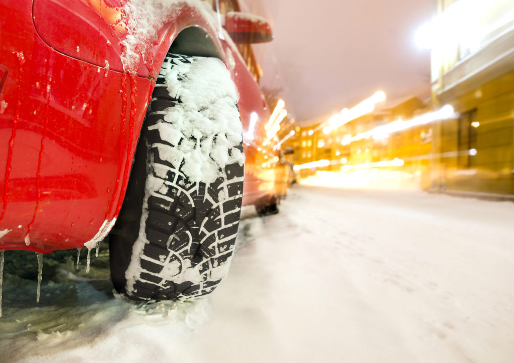 Rode auto met besneeuwde winterbanden