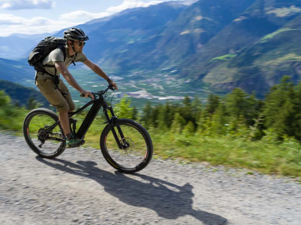 man fietst elektrische mountainbike door alpen Man fietst op een elektrische mountainbike door de Alpen