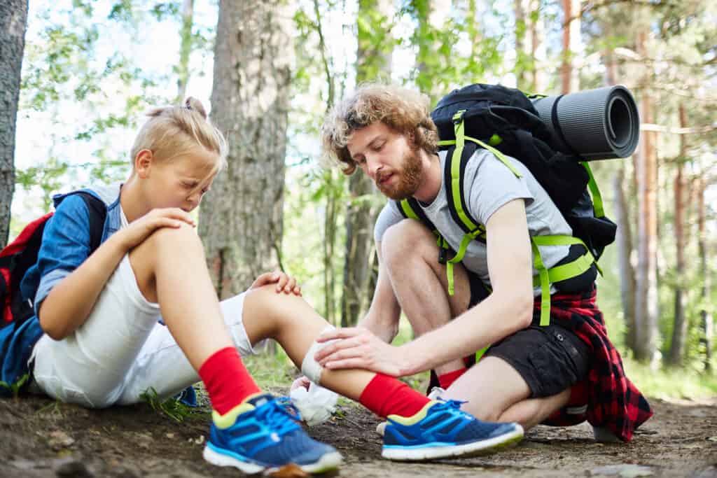 meisje krijgt verband om haar been haar vader bos Meisje krijgt verband om haar been van haar vader in het bos