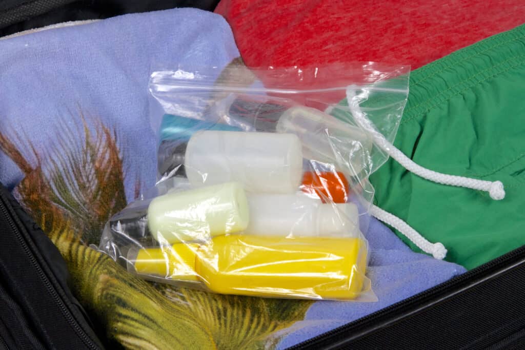 Vloeistoffen in een doorzichtig gripzakje in een koffer met kleding
