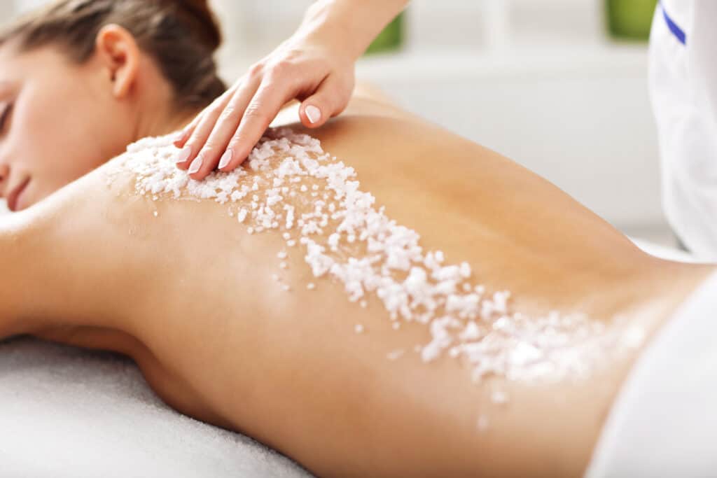 blonde vrouw krijgt zoutscrub tijdens massage Blonde vrouw krijgt een zoutscrub tijdens een massage