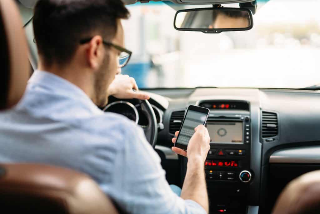 man heeft een telefoon in de hand in de auto Man heeft een telefoon in de hand in de auto