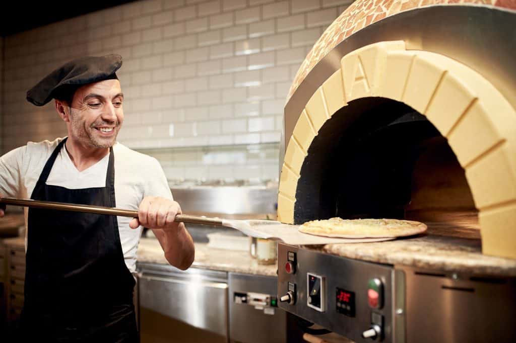 pizzabakker schuift pizza oven Pizzabakker schuift een pizza in de oven