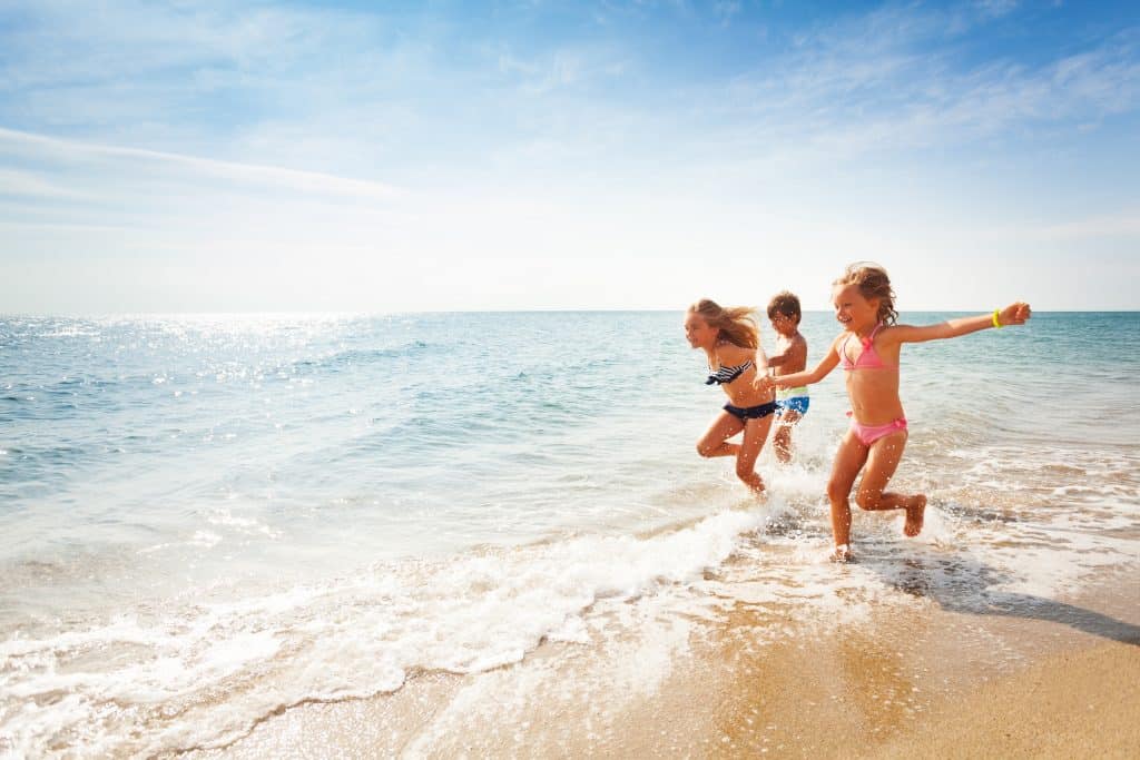 kinderen rennen door branding bij strand Kinderen rennen door de branding bij het strand