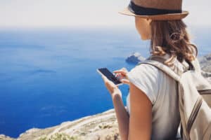 Vrouw met telefoon bij een klif met uitzicht op zee