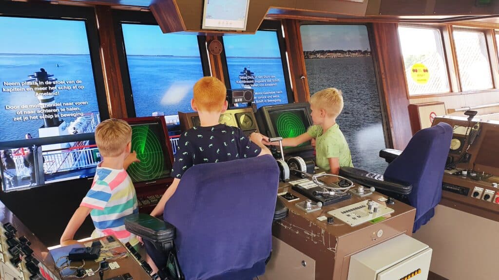 drie kinderen aan het spelen op een simulator van een veerboot in het abraham fock museum Drie kinderen aan het spelen op een simulator van een veerboot in het Abraham Fock museum
